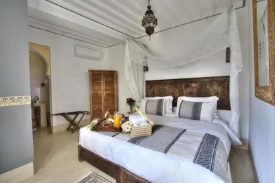a bedroom with a large bed with a wooden headboard at Riad Mazarin des gourmets in Marrakech