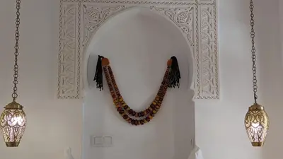 a wall with a moroccan mirror and two lights at Riad Dar Eternity in Marrakech