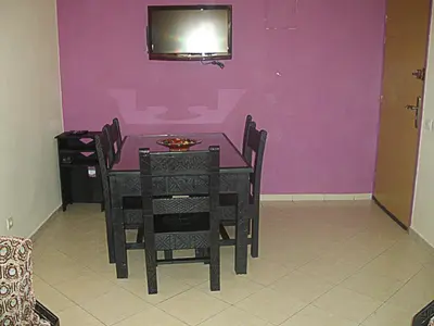 a dining room table with chairs and a tv on a purple wall at Appartement Aïda in Marrakech