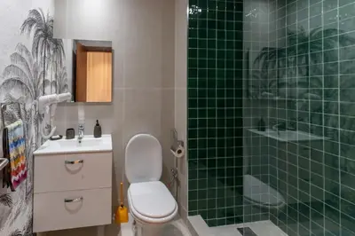a bathroom with a toilet and a green tiled shower at Cozy Golf Apartment Wifi 4k-TV Netflix in Marrakech