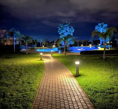 a brick pathway with lights in a park at night at Cozy Golf Apartment Wifi 4k-TV Netflix in Marrakech