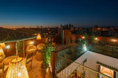 a balcony with a view of the city at night at Riad dar El Arsa Rooftop & jacuzzi in Marrakech
