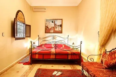 a bedroom with a red bed and a couch at Riad La Kahana in Marrakech