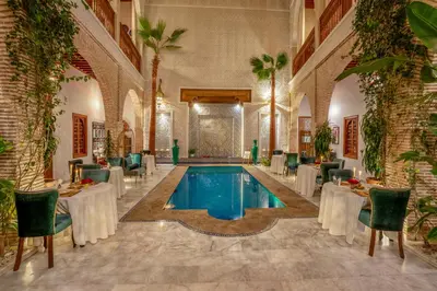 a pool in a room with tables and chairs at Riad Janate & SPA in Marrakech