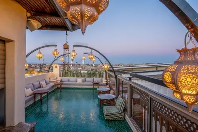 a resort balcony with a pool and chandeliers at Riad Janate & SPA in Marrakech