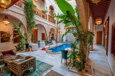 a hotel lobby with a pool and tables and plants at Riad Janate & SPA in Marrakech