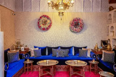 a room with a blue couch and tables and a chandelier at Riad Janate & SPA in Marrakech