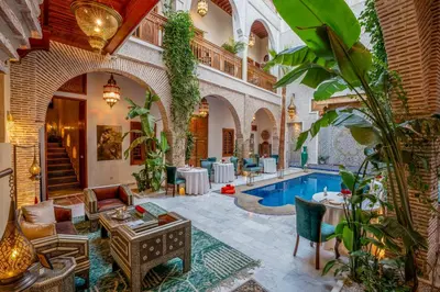 a hotel lobby with a pool and tables and chairs at Riad Janate & SPA in Marrakech