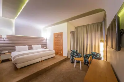 a hotel room with a bed and a desk and chairs at Hôtel Ibn Batouta in Marrakech