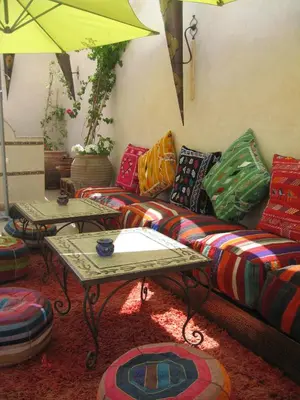 a living room with a couch with colorful pillows and tables at RIAD MAKENE MOUCHKILL in Marrakech