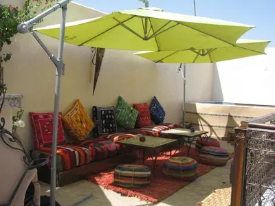a patio with a couch and an umbrella at RIAD MAKENE MOUCHKILL in Marrakech