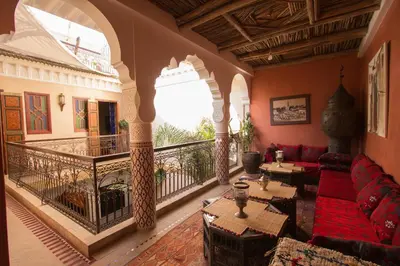 a living room with a red couch and a balcony at RIAD MAKENE MOUCHKILL in Marrakech