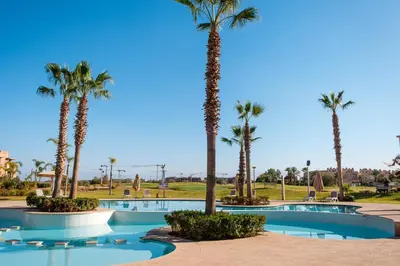 a swimming pool with palm trees in a resort at Coup de cœur à Marrakech - idéal famille et couple in Marrakech
