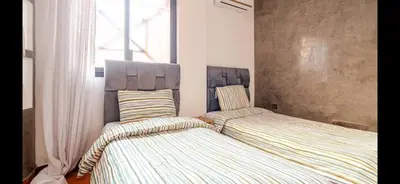 two beds sitting next to each other in a bedroom at Appart Kech Village in Marrakech