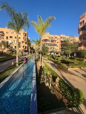 a swimming pool in a street with palm trees and buildings at Appart Kech Village in Marrakech
