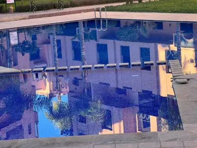 a reflection of a building in a swimming pool at Appart Kech Village in Marrakech