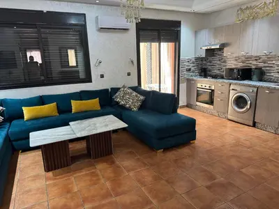 a living room with a blue couch and a table at Appart Kech Village in Marrakech