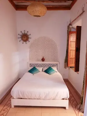 a bedroom with a white bed with blue pillows at DAR MAR'OUKA , Maison d'hôtes in Marrakech