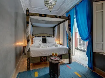 a bedroom with a canopy bed with blue curtains at Riad Princesse Du Désert & Spa in Marrakech