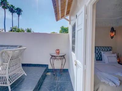 a porch with a bed and a table and a chair at Riad Princesse Du Désert & Spa in Marrakech