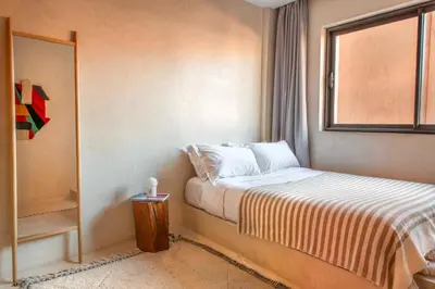 a small bedroom with a bed and a window at Appartements Brummell Marrakech in Marrakech