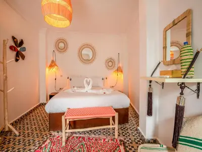 a bedroom with a bed and a stool and a mirror at Riad Art & Emotions in Marrakech