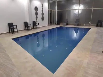 a large pool with blue water in a room with chairs at Opéra Appartement, Hivernage Marrakech. in Marrakech