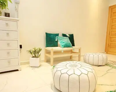 a living room with a chair and a ottoman at RIAD Miel & Une Nuit in Marrakech