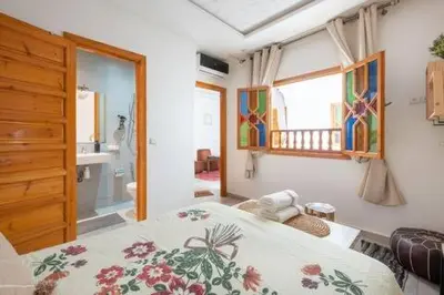 a bedroom with a bed and a bathroom with a window at RIAD Miel & Une Nuit in Marrakech