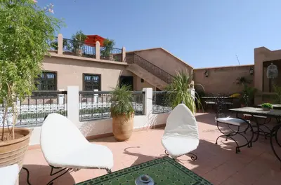a patio with two white chairs and a table at Riad Baba Ali & Spa in Marrakech