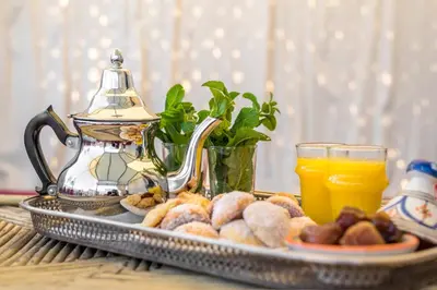 a tray of food with a tea pot and orange juice at Riad Hissan in Marrakech