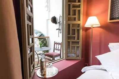 a room with a bed and a window with a chair at Riad Hissan in Marrakech
