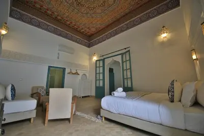 a bedroom with two beds and a table and a chair at Riad 5 GÉNÉRATIONS in Marrakech