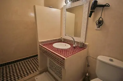 a bathroom with a sink and a mirror and a toilet at Riad 5 GÉNÉRATIONS in Marrakech