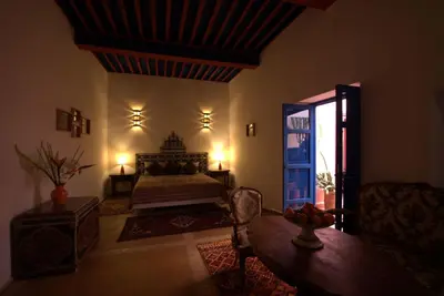 a bedroom with a bed and a table and a mirror at Riad Aventurine in Marrakech