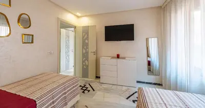 a bedroom with two beds and a television on the wall at AiM HOUSE in Marrakech