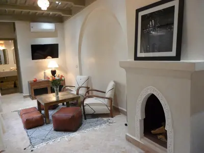 a living room with a fireplace and a table and chairs at Riad et Spa Misria Les Oliviers in Marrakech