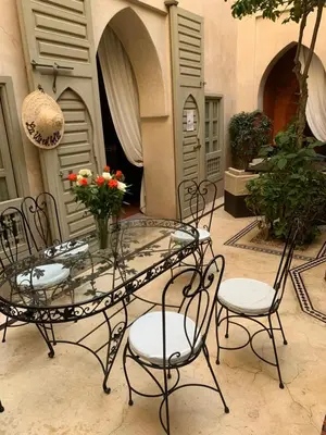 a glass table and chairs with a vase of flowers at Riad et Spa Misria Les Oliviers in Marrakech