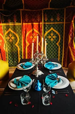 a table with a black table cloth with candles and blue napkins at Riad Papillon by Marrakech Riad in Marrakech