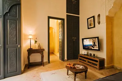 a living room with a tv and a door at Riad Cinnamon by Marrakech Riad in Marrakech