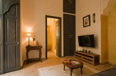 a living room with a tv and a door at Riad Cinnamon by Marrakech Riad in Marrakech