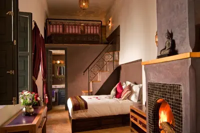 a bedroom with a bed and a fireplace in it at Riad Cinnamon by Marrakech Riad in Marrakech
