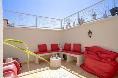 a room with red cushioned chairs and a table on a balcony at Résidence alqaria assiyahiya full private riad in Marrakech