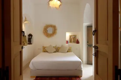 a bedroom with a white bed and a mirror at Riad NaaNaa Bed & Breakfast in Marrakech
