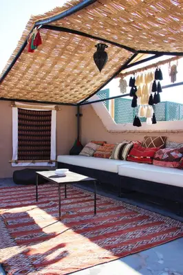 a room with a bed and a table on a rug at Riad El Ouarda in Marrakech