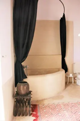 a bath tub in a room with a curtain at Riad El Ouarda in Marrakech