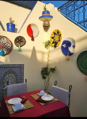 a table with plates and dishes on a wall with plates and bowls at Riad Eva in Marrakech