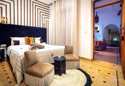 a bedroom with a large bed and two chairs at Riad La Croix Berbere Deluxe in Marrakech