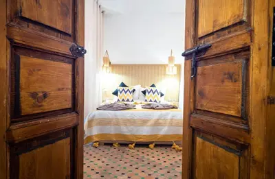 a bedroom with a bed with blue and white sheets at Riad La Croix Berbere Deluxe in Marrakech