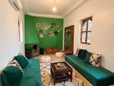 a living room with a green couch and a fireplace at RIAD ZEFYR in Marrakech